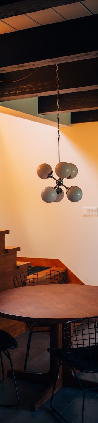 round brown wooden table and chairs under white pendant lamp