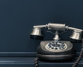 black and brown rotary phone near gray wall